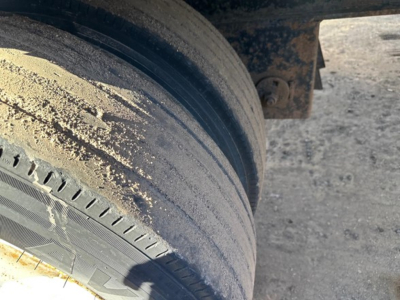 Trailer wheel and wheel well with muddy dirt, twin tires visible on a utility flatbed trailer.