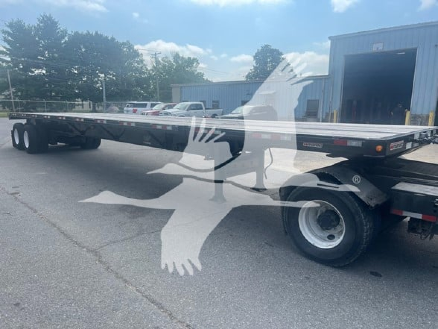 Manac air ride extendable flatbed trailer in a side view showing long aluminum deck, rear dual axles, and wheel/tire assemblies.