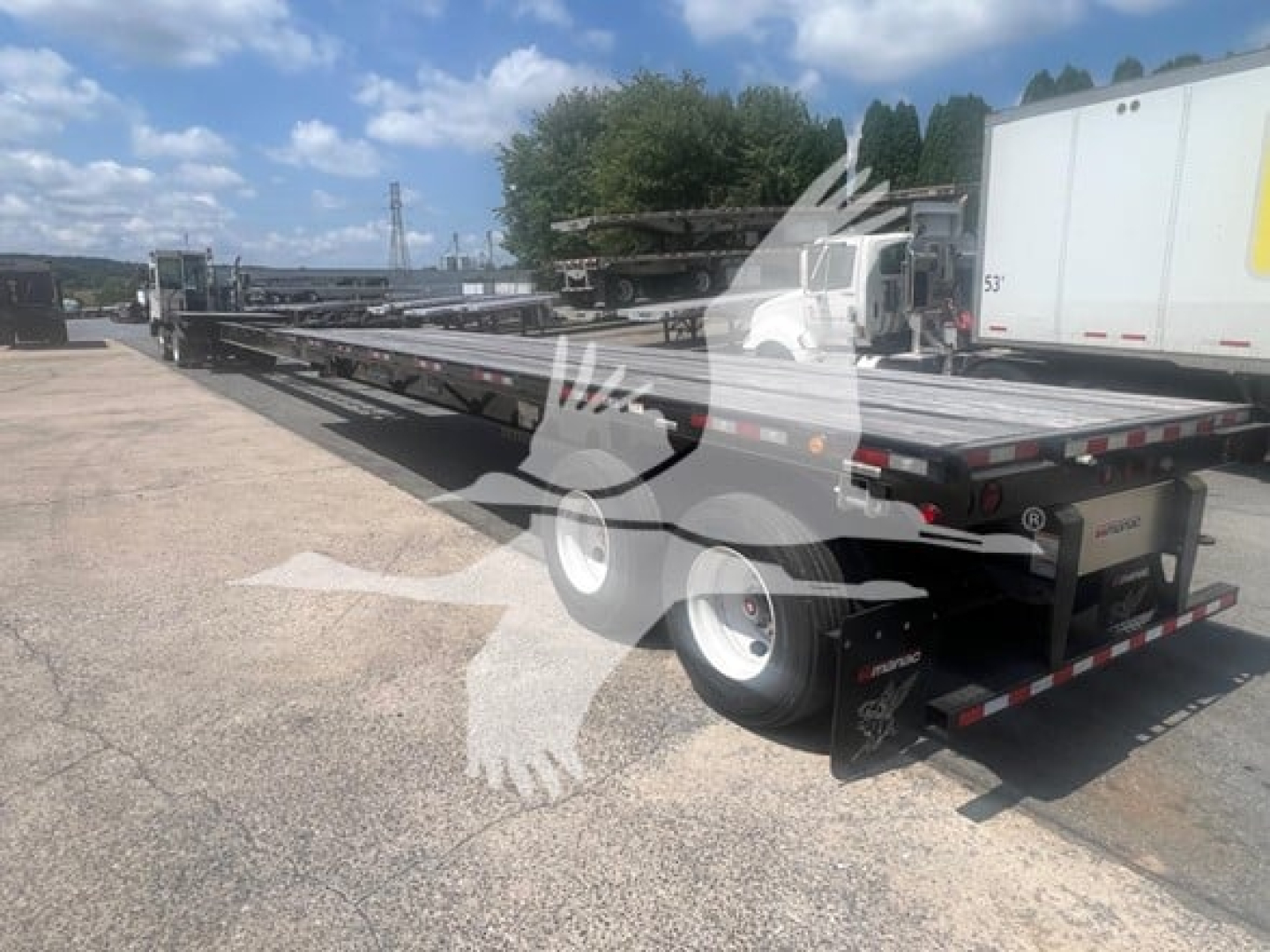 Manac air ride extendable flatbed trailer in a parking lot, side view showing extendable deck and rear with lights.