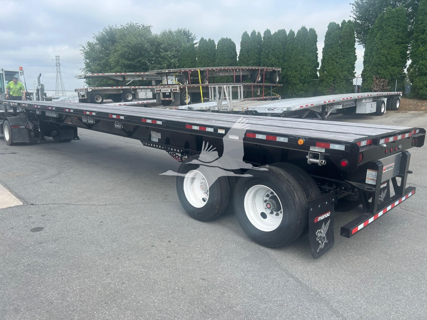 Manac extendable flatbed trailer with air ride suspension and dual rear axles, rear view showing taillights, mud flaps, and reflective tape.
