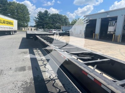 Truck trailer chassis with extendable flatbed showing open frame and hydraulic components.