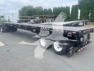 Flatbed trailer with extendable deck and air ride suspension, dual rear axles, black frame, white wheels, and reflective tape along edges.