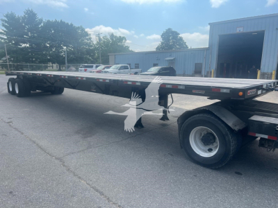 Manac air ride extendable flatbed trailer seen from side with extendable deck and multiple axles.