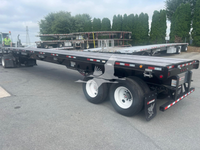Manac extendable flatbed trailer with air ride suspension and dual rear axles, rear view showing taillights, mud flaps, and reflective tape.