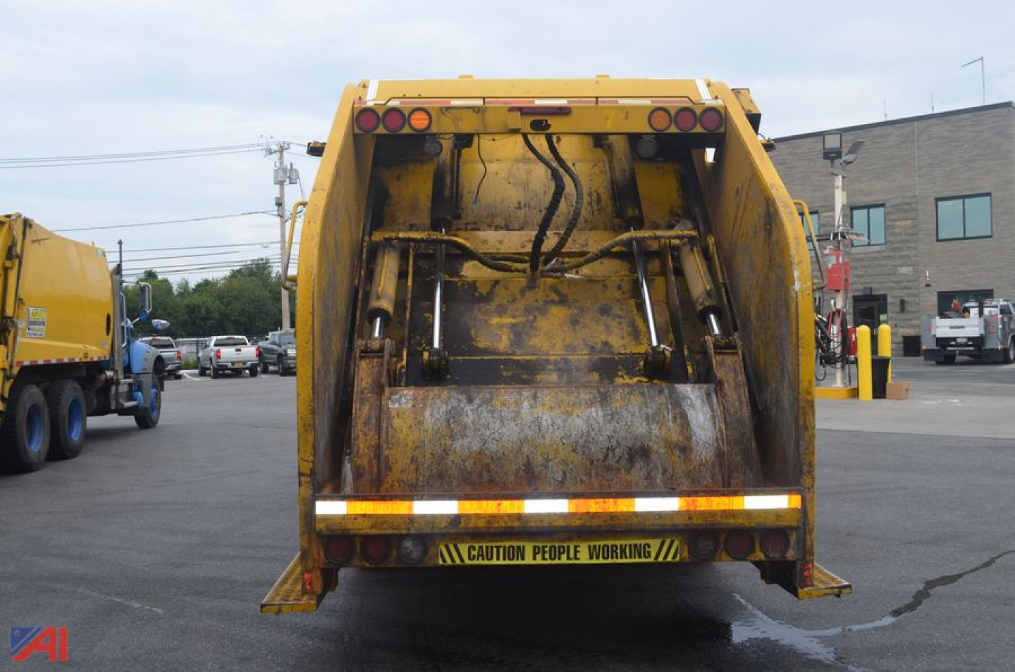 Rear view of a yellow Mack Granite dump truck with tailgate and warning label, in-service condition.