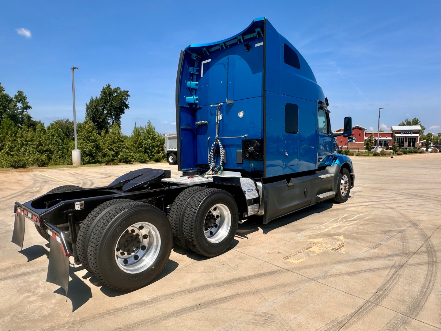 Peterbilt 579 tractor with blue sleeper cab and dual rear axles, side view showing rear wheels and chassis.