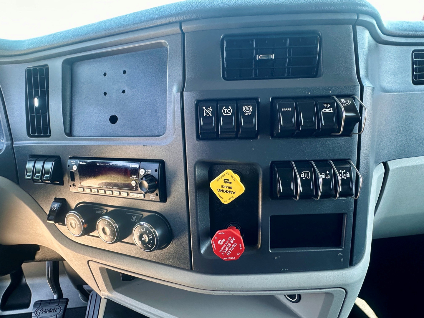 Peterbilt 579 dash area showing control switches, ignition keys, and dashboard panels with a yellow air filter reminder tag; cabin interior visible.