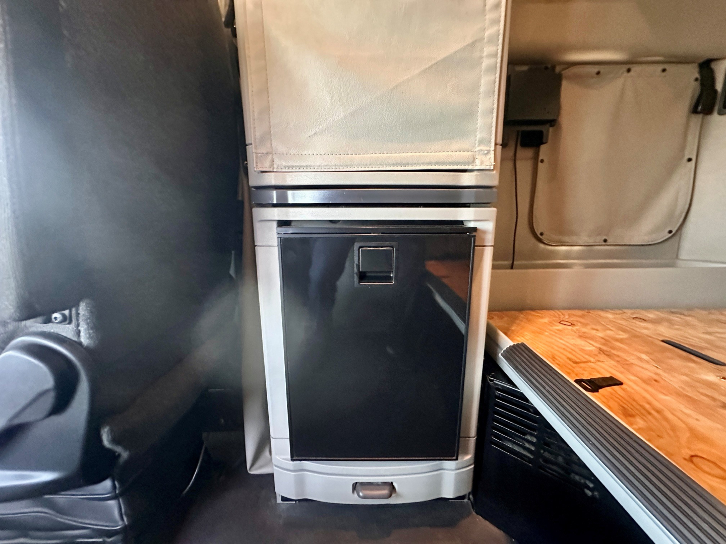 Peterbilt 579 interior rear area showing storage cabinet with black front panel and wood deck platform inside a sleeper cab.