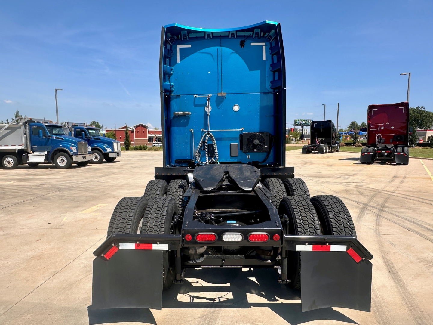 Peterbilt 579 rear view showing fifth wheel, dual rear axles with dual tires, and mud flaps in a truck lot.