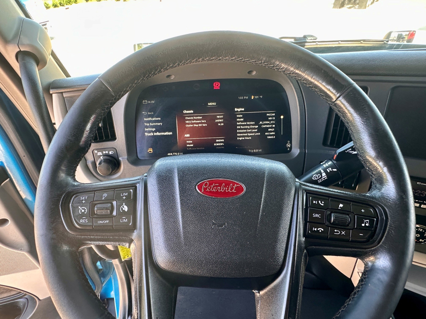 Peterbilt steering wheel and instrument cluster showing digital displays with information; center badge 'Peterbilt' on wheel.