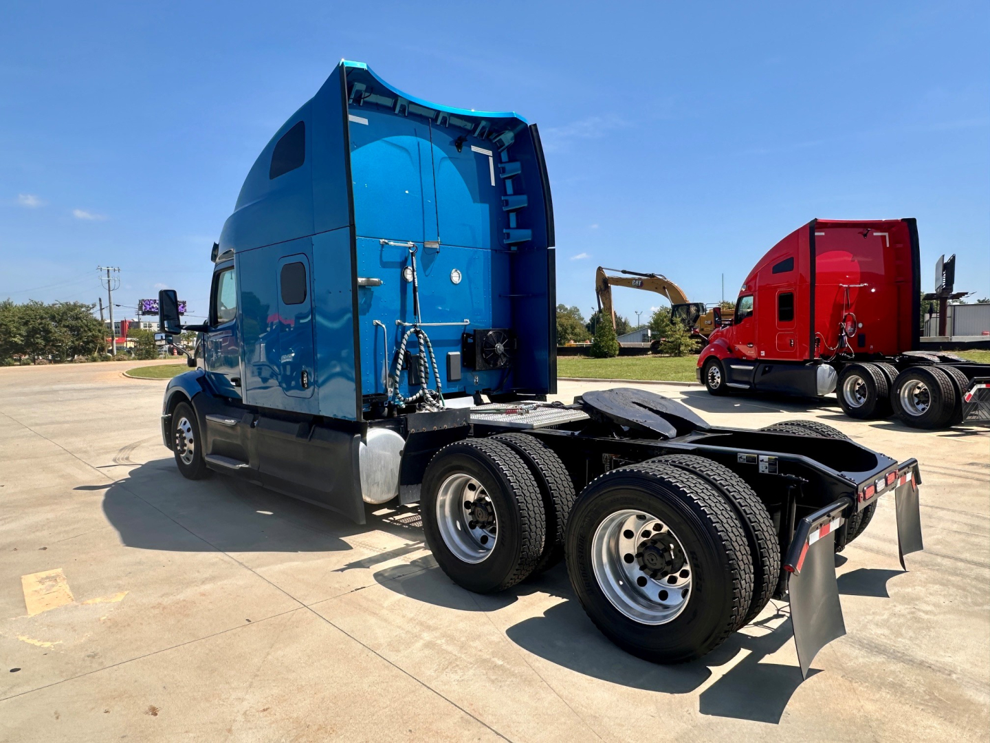 Peterbilt 579 tractor in blue, semi-truck cab with fifth wheel and dual rear axles, chrome fuel tanks, in-service on concrete lot.