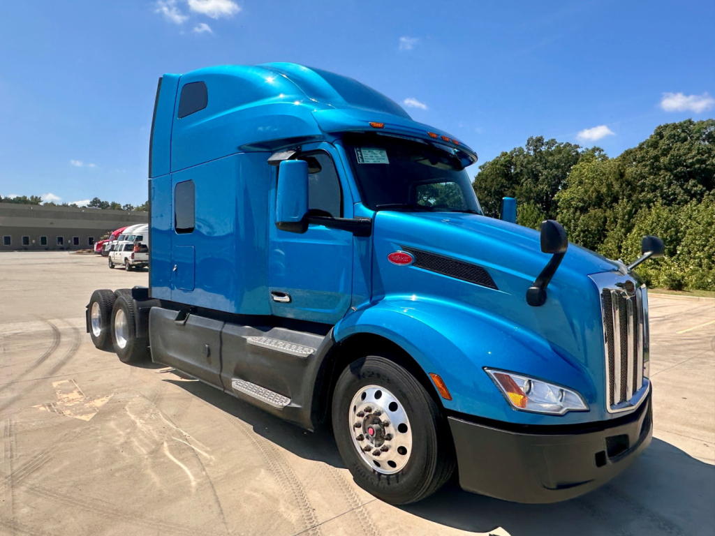 Peterbilt 579 tractor unit in blue, side view showing sleeper cab and front grille.