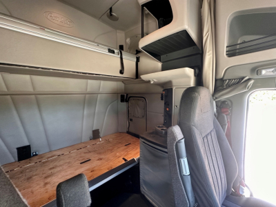 Peterbilt 579 cabin interior showing sleeper area with overhead cabinetry and bunk table.