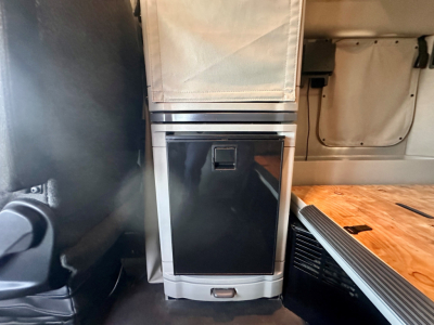 Peterbilt 579 interior rear area showing storage cabinet with black front panel and wood deck platform inside a sleeper cab.