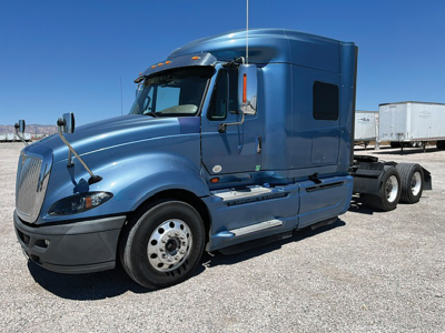 Truck cab showing 2015 International ProStar122 in blue with sleeper, front wheel, and trailer in background.