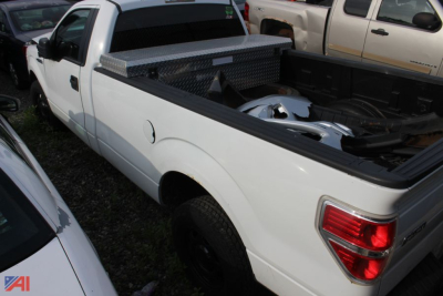 Ford F-150 pickup truck 2012 white with bedTools and toolbox visible in bed. Side view of rear quarter showing taillight and truck bed contents.
