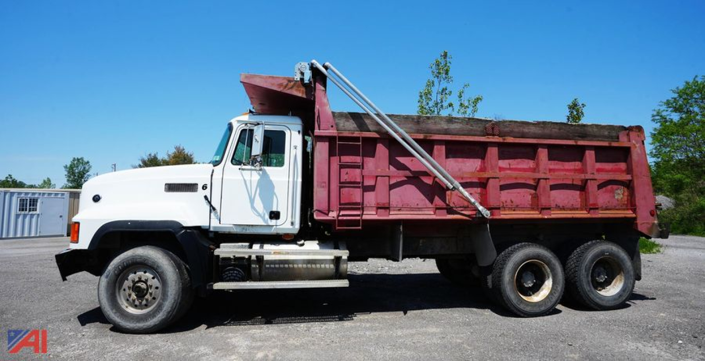 Dump truck with white cab and red dump bed, side view showing Mack CL713 chassis and six wheels.
