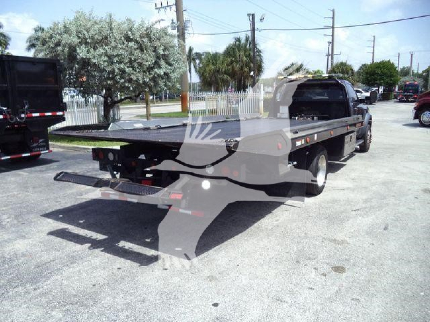 Ram 5500 rollback tow truck platform rear view showing flatbed with black hydraulic components and rear bumper.