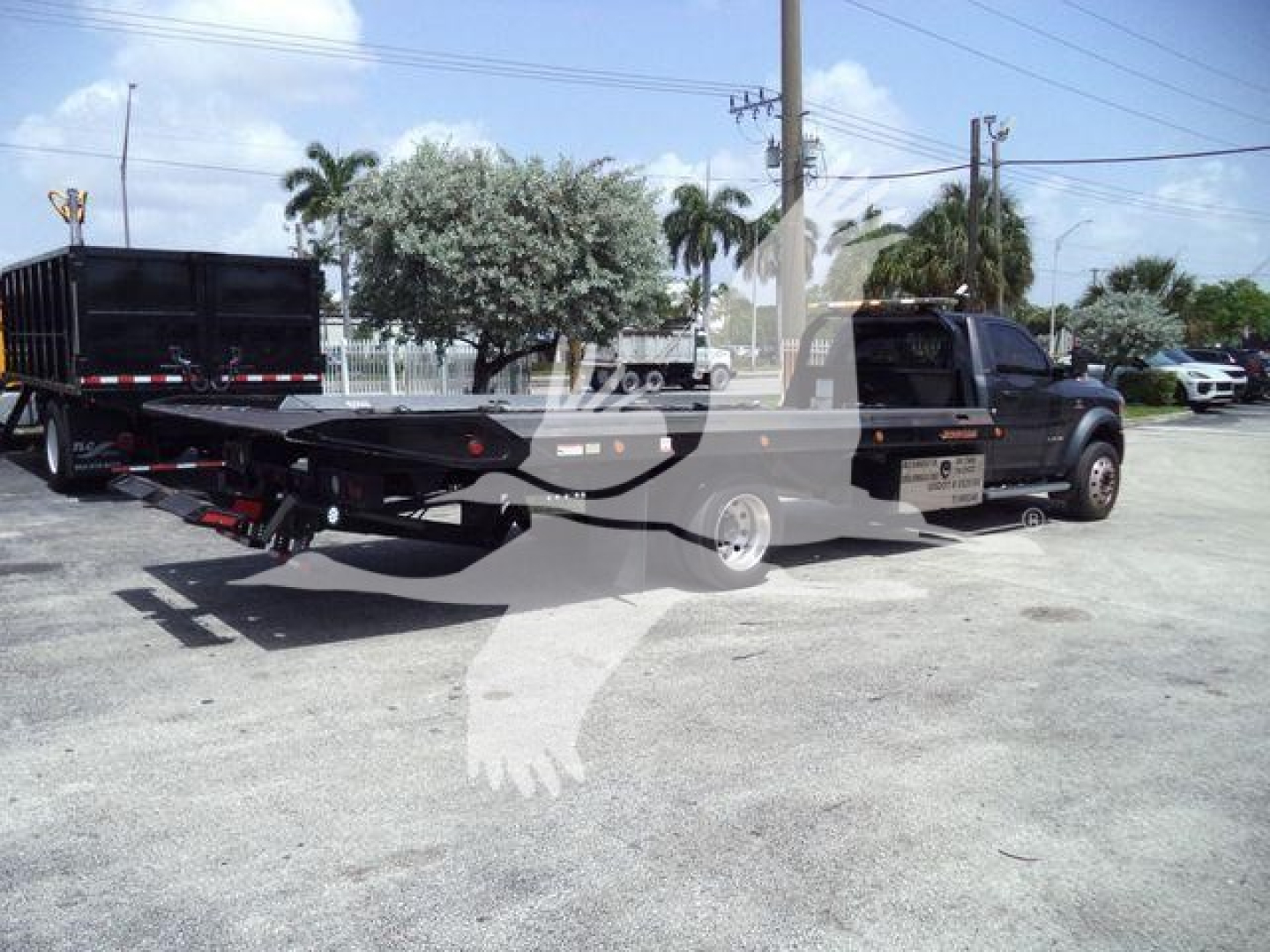 Ram 5500 rollback tow truck with flatbed in truck lot, dual rear wheels, black cab, VIN 3C7WRMDL6NG380480 visible on listing