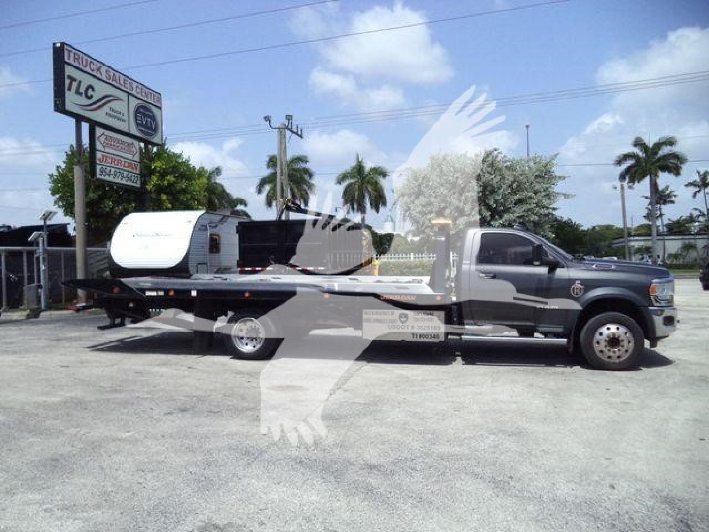 Ram 5500 SLT rollback truck with flatbed and crane, side view.