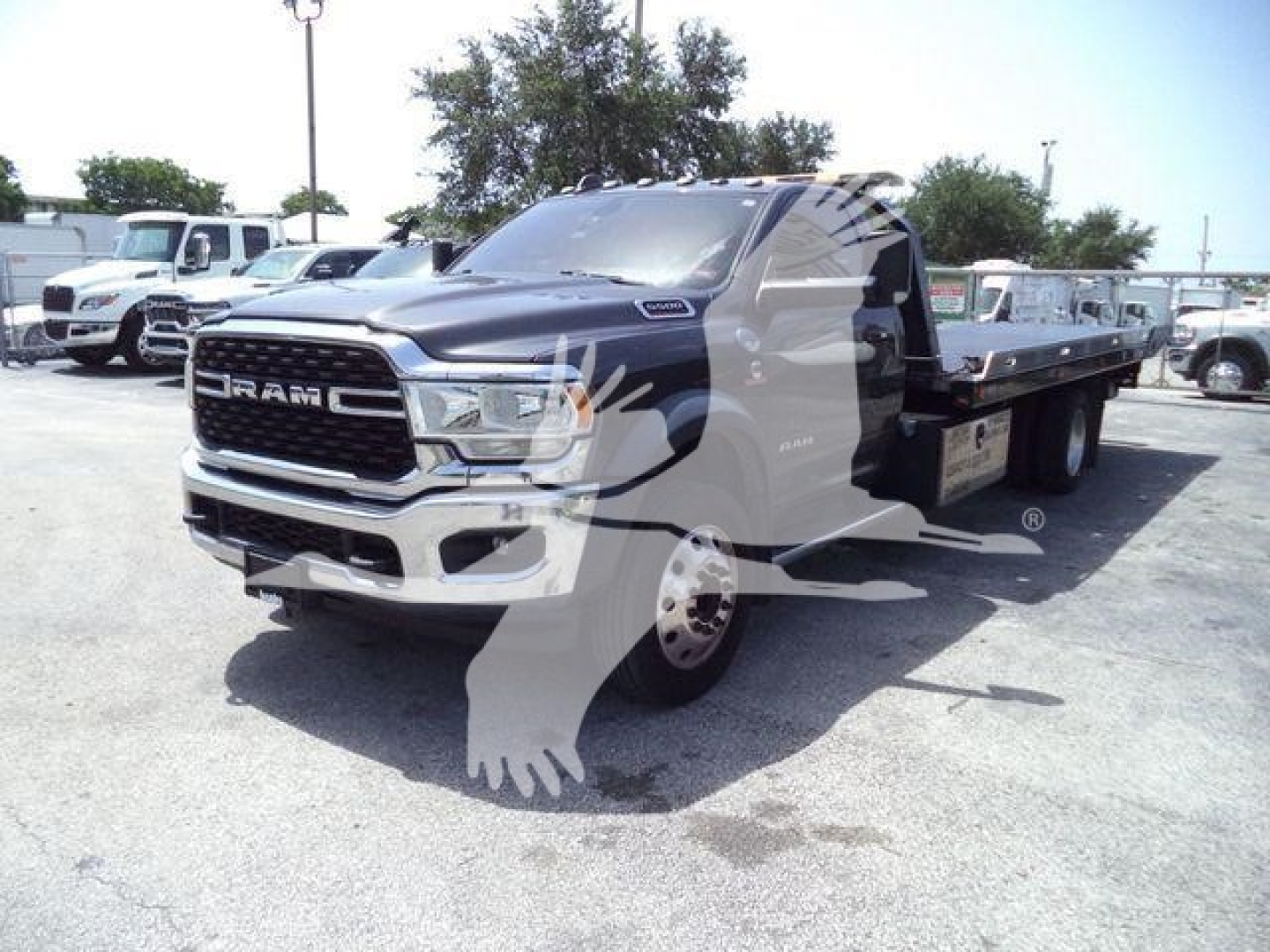 Ram 5500 tow truck in a lot with a flatbed, front grille shows RAM lettering and chrome bumper.
