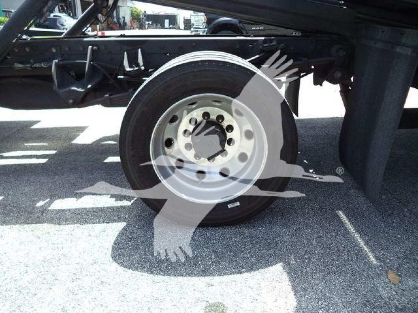 Wheel and undercarriage of a Ram 5500 rollback truck showing front wheel with wheel hub and tire, chassis frame, and shadowed components.