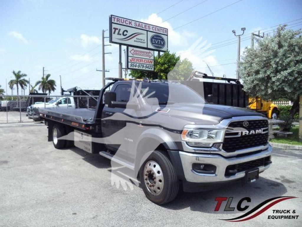 Ram 5500 tow truck flatbed in a dealership lot showing front grille RAM logo and side mirrors.