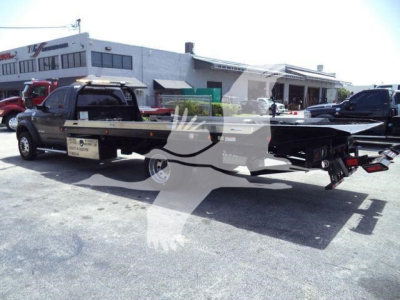 Ram 5500 rollback truck in a dealership lot with a long flatbed and rear equipment visible.