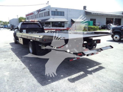 Ram 5500 rollback tow truck with flatbed viewed from rear-left side, showing long flatbed and rear lights.