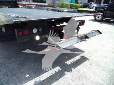 Ram 5500 rollback flatbed shows rear lights and platform edge with metal diamond plate and taillight assemblies.