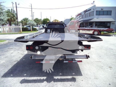 Truck bed of a Ram 5500 rollback showing dual rear ramps and towing equipment, rear view