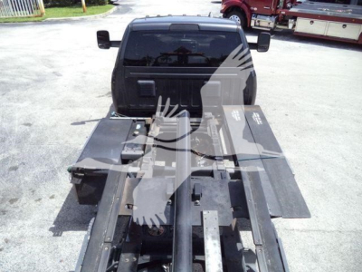 Truck bed with roll-back equipment attached to a Ram 5500 truck, showing the hydraulic frame and platform rails.