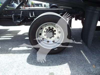 Wheel and undercarriage of a Ram 5500 rollback truck showing front wheel with wheel hub and tire, chassis frame, and shadowed components.