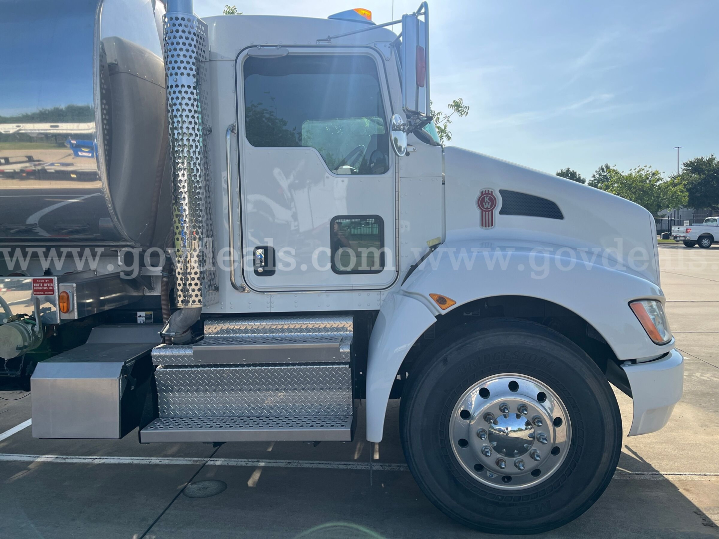Kenworth T370 truck side view showing cab and front wheel, chrome exhaust stack, diamond plate steps, and a side emblem on the hood.