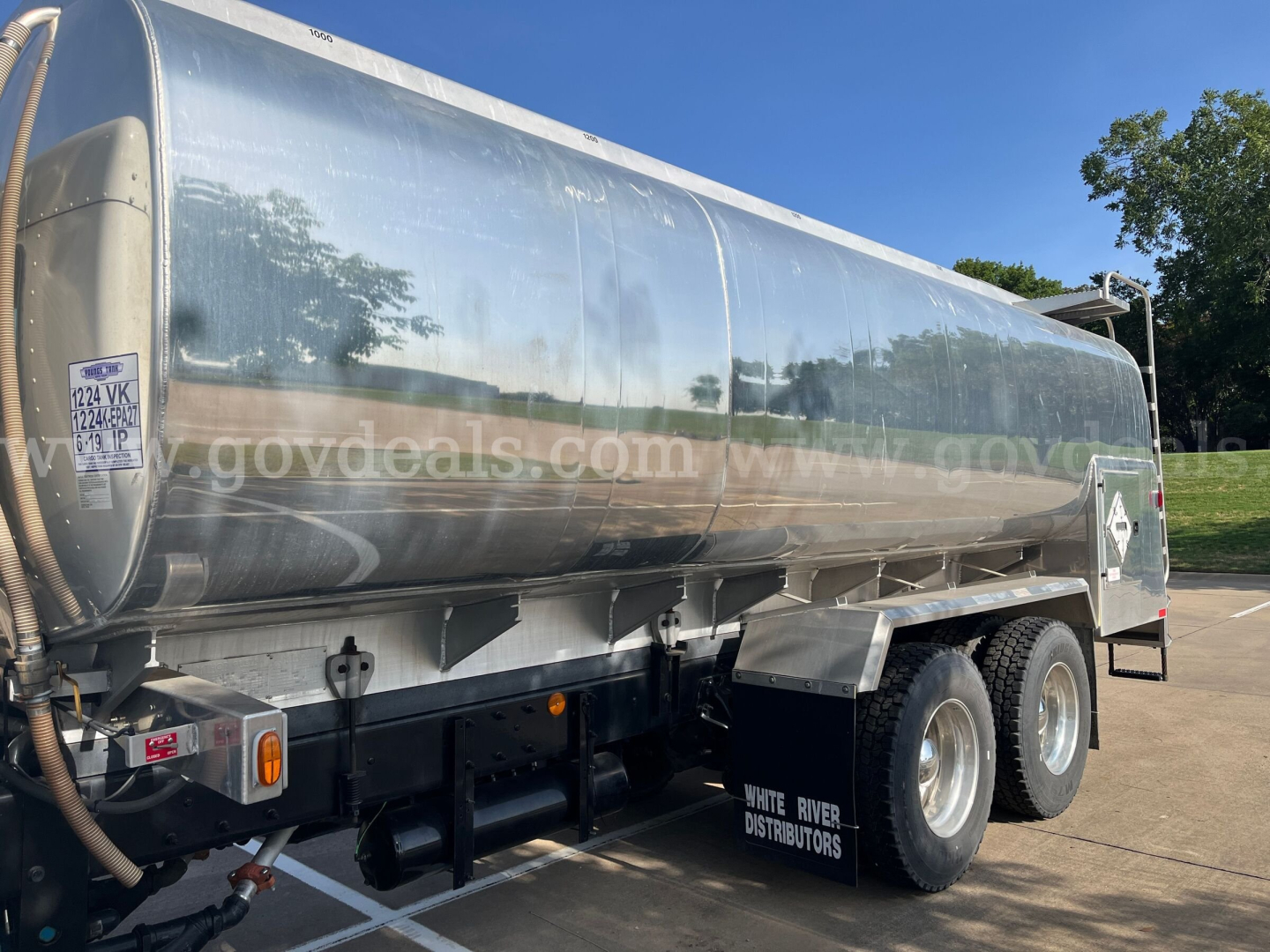 Kenworth T370 tanker truck in-service vehicle with a polished aluminum tank showing White River Distributors mudflaps and dual rear axles.