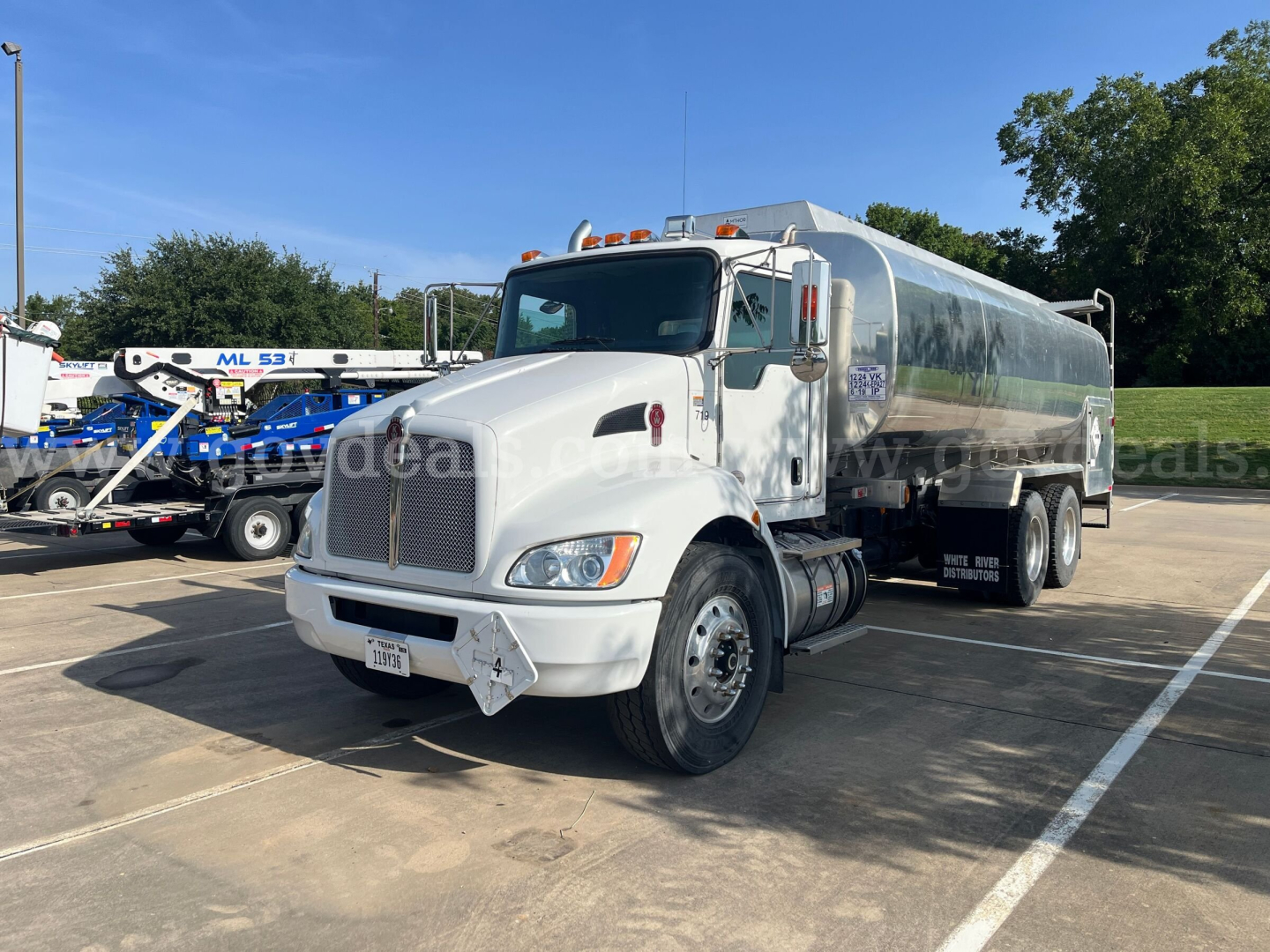 Kenworth T370 medium-duty tanker truck in white, front-left view, with chrome grille, dual rear wheels, and tanker tank; appears in a dealership lot.