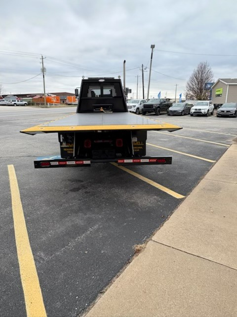 Back view of a 2025 Hino L7 rollback truck with a flatbed and platform, showing rear bumper lights and hitch area.