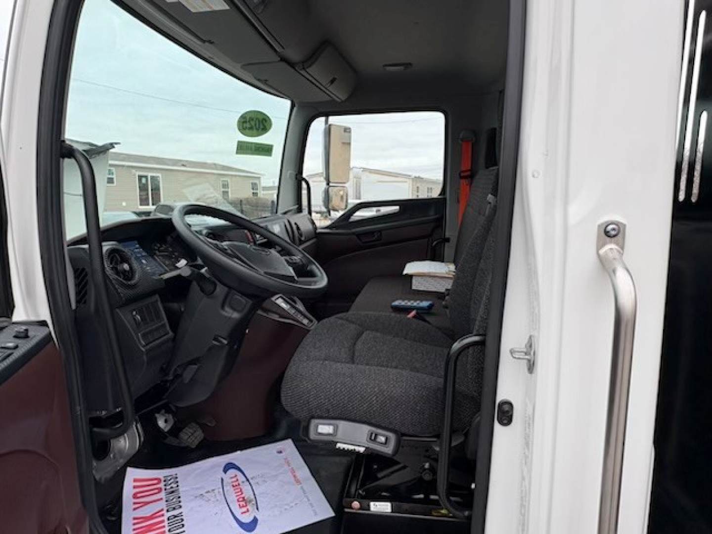 Truck cab interior of a 2025 Hino L7 showing steering wheel, driver's seat, and controls.