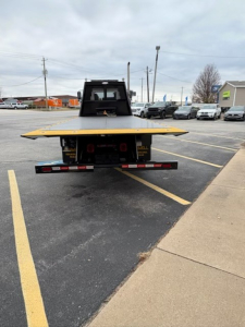 Back view of a 2025 Hino L7 rollback truck with a flatbed and platform, showing rear bumper lights and hitch area.