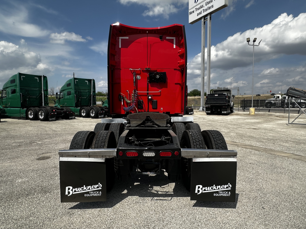 Peterbilt 579 rear view showing fifth wheel and dual rear mud flaps with Bruckner’s Truck Equipment branding, red sleeper cab, highway trucks lot.