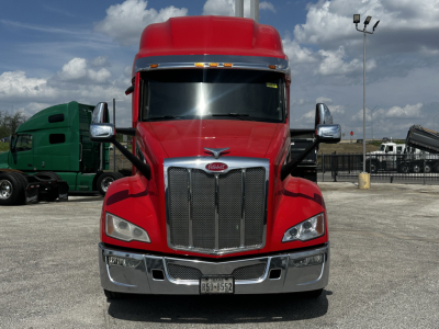 Peterbilt 579 truck front view showing bold grille, red cab, chrome bumper, and large windshield.