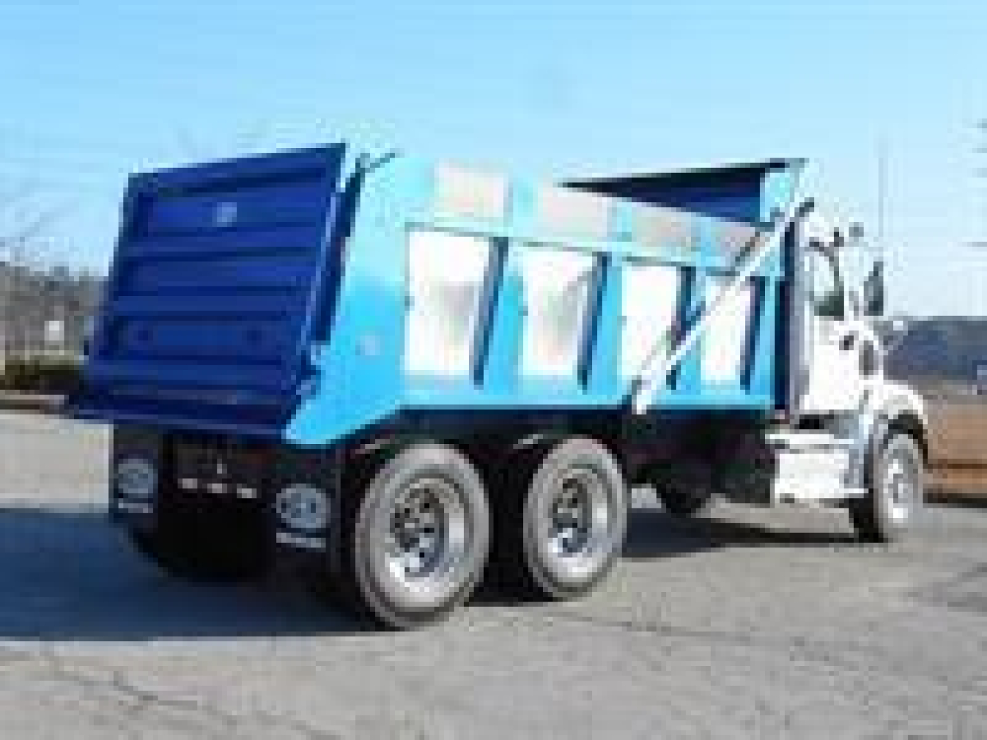 Blue dump truck rear/side view showing cargo bed and wheels; no legible labels or serials visible.