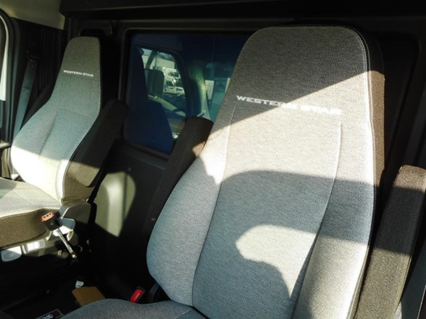 Truck cab interior showing light gray cloth seats with 'WESTER STAR' branding on headrests and door area visible.