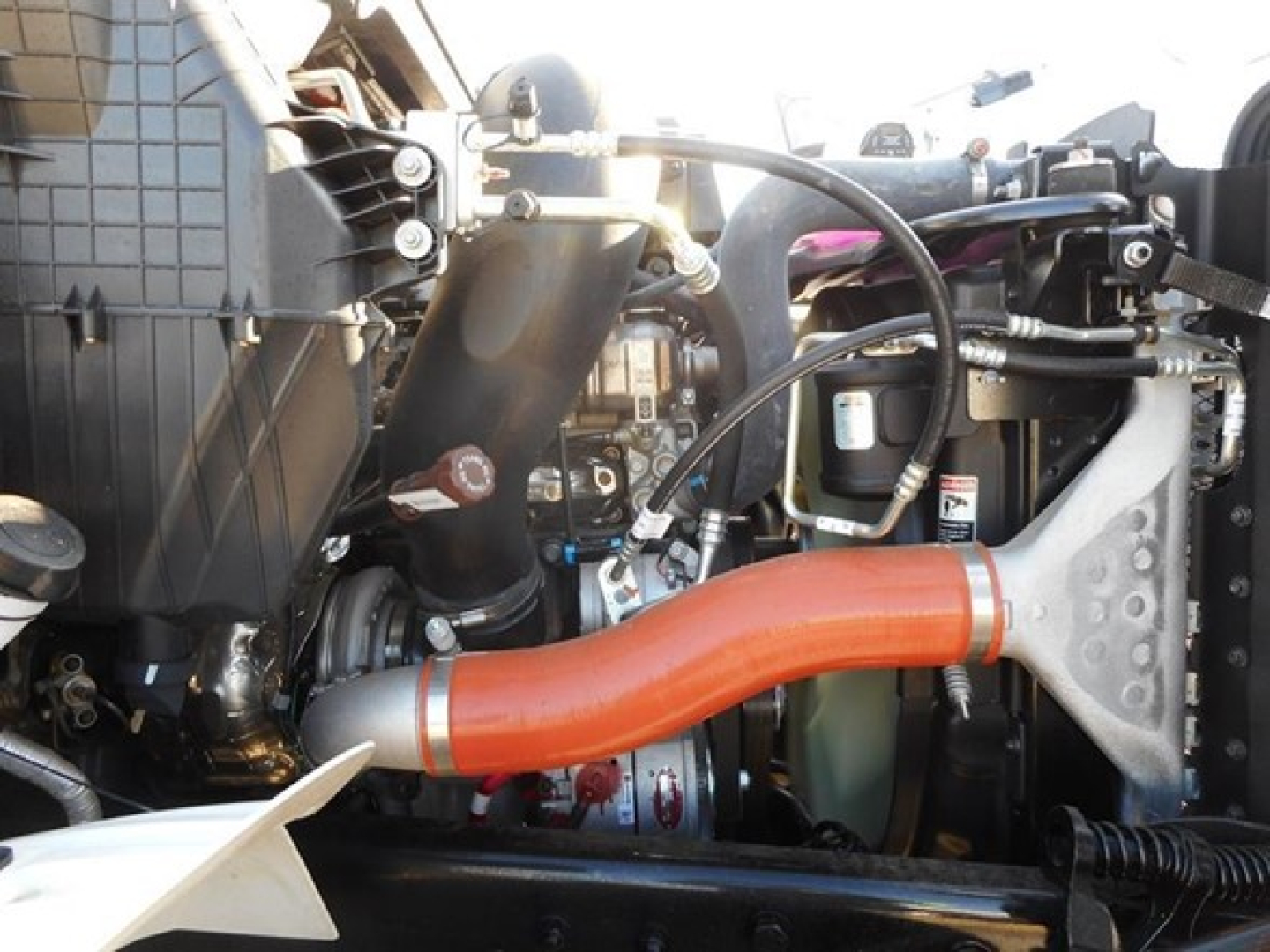 Engine bay of a 2026 Western Star 47X dump truck showing bright orange intake tube and surrounding components.