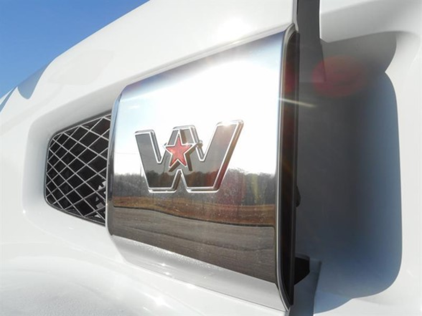 Front corner of a white Western Star 47X truck showing the chrome grille badge with a star and the letter W on the hood.