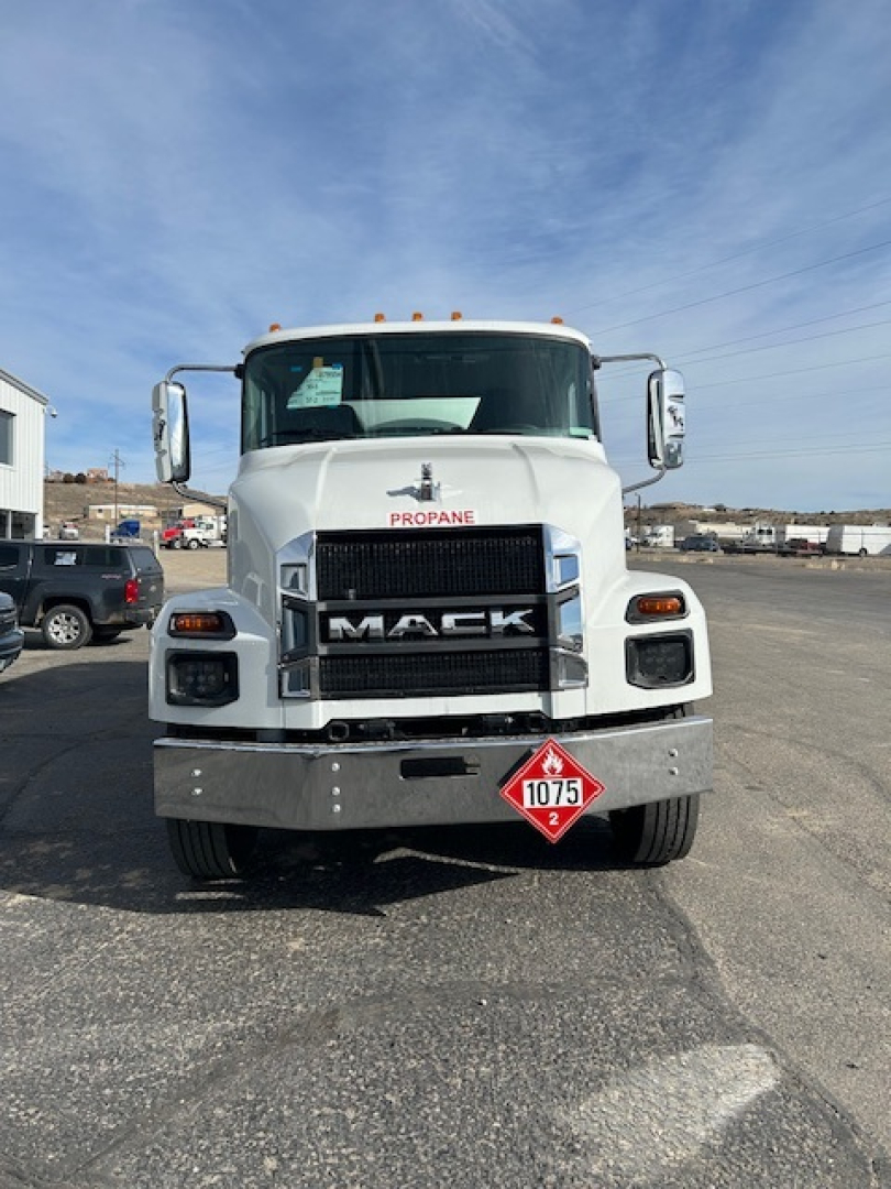 Front view of a white 2026 Mack MD7 truck showing Mack grille, DEF/propane label on the hood, and hazard placard on bumper.