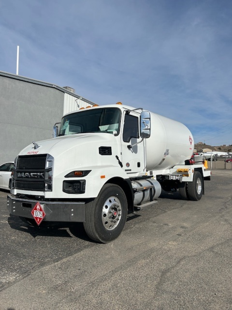 Mack MD7 fuel tanker truck in a parking lot showing front and side view with white cab and cylindrical tank.