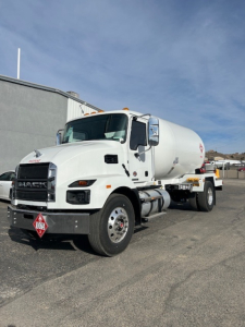 Mack MD7 fuel tanker truck in a parking lot showing front and side view with white cab and cylindrical tank.