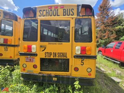 Back view of a yellow school bus with STOP ON SIGNAL text and emergency door label, letters SCHOOL BUS across top, red taillights, rear windows, license plate visible.