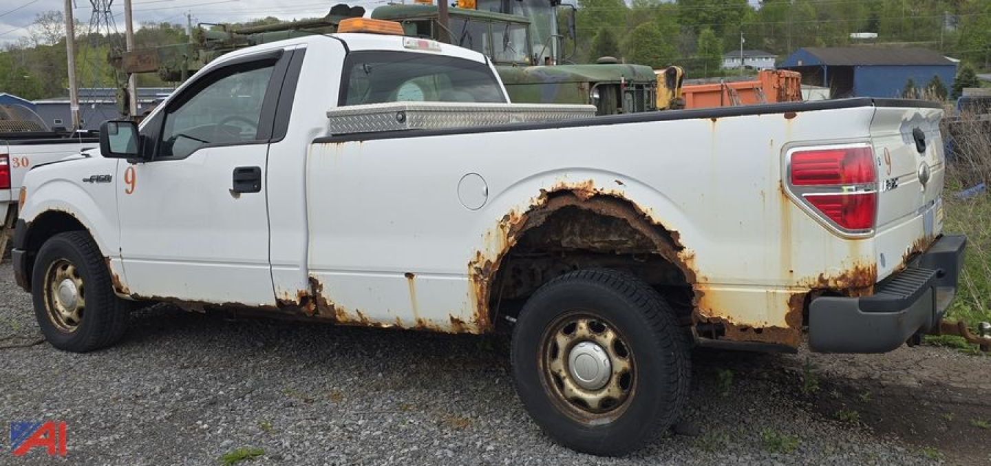 Ford F-150 XL pickup truck 2011 side view with rust around rear wheel well and cargo bed, two-tone white body, utility bed with toolbox, single cab.